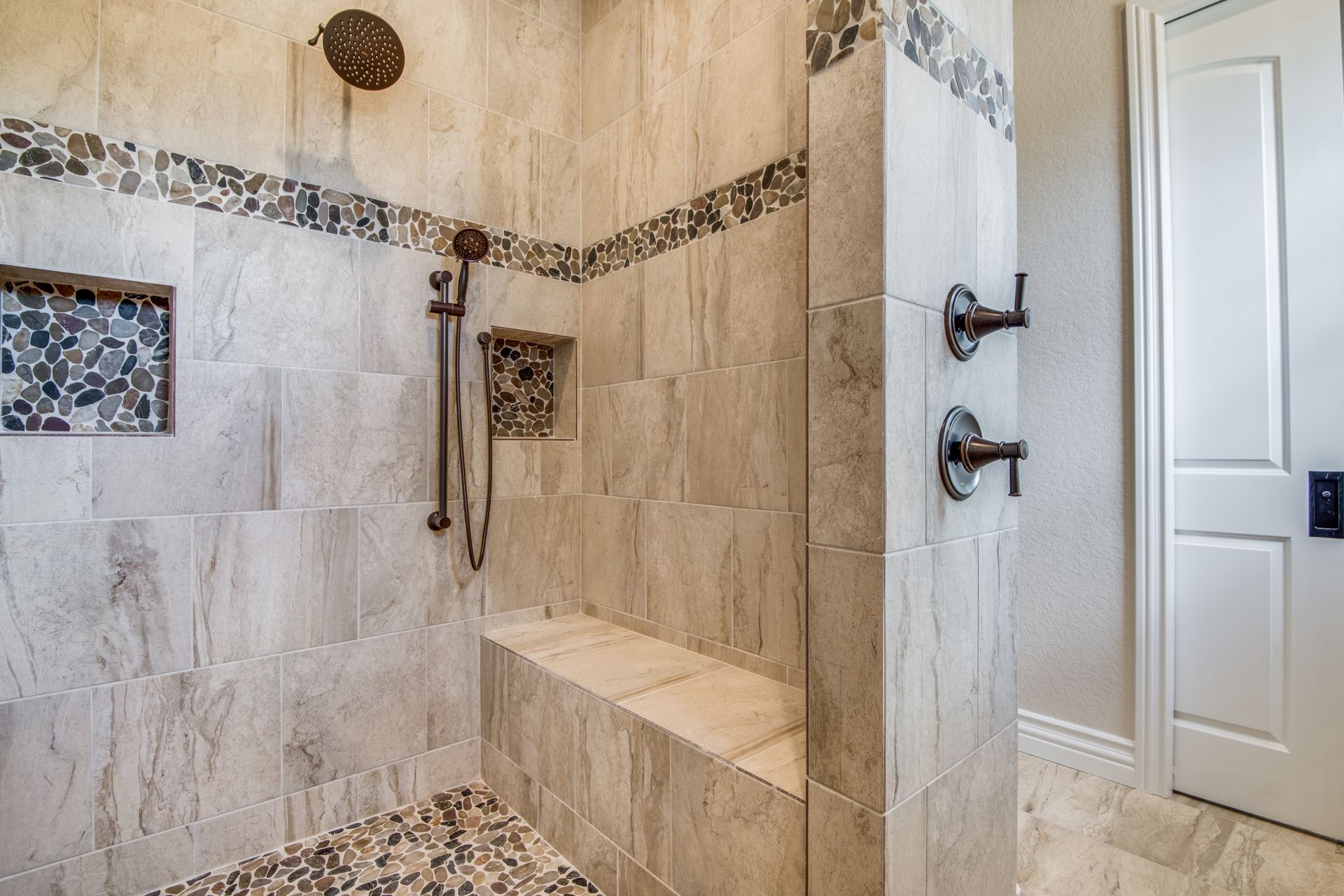 A walk in shower with a bench and a shower head.