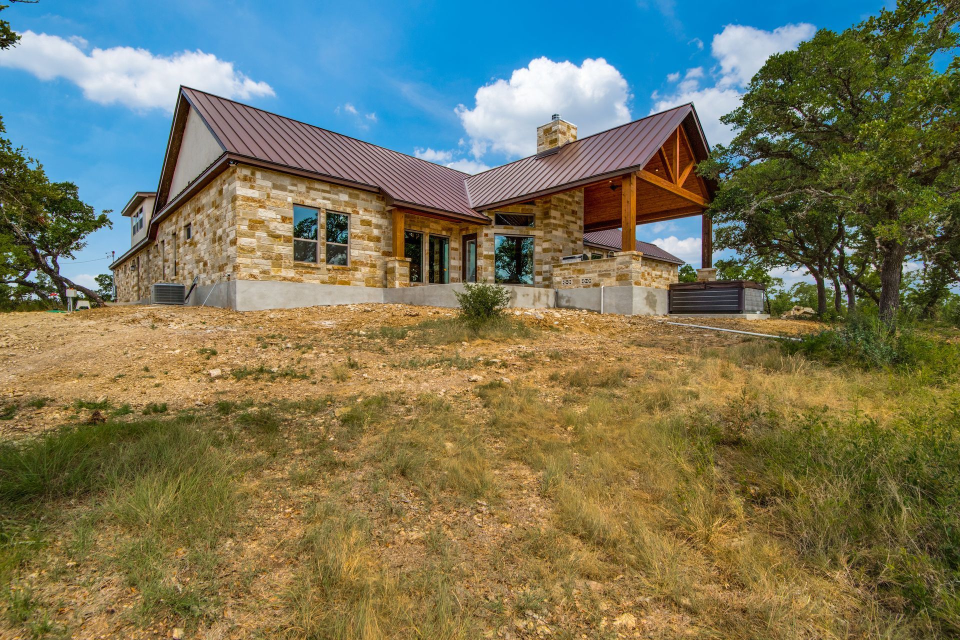 A large stone house with a brown roof is sitting on top of a grassy hill.