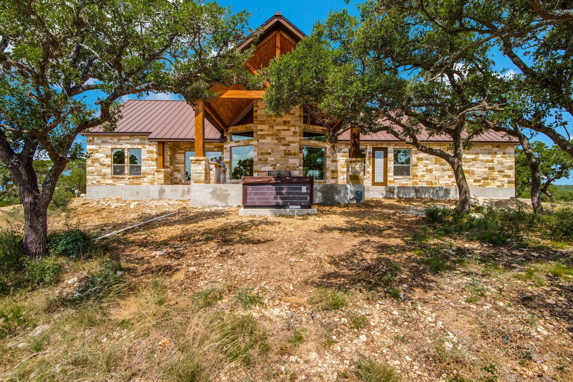 A large stone house is sitting on top of a hill surrounded by trees.