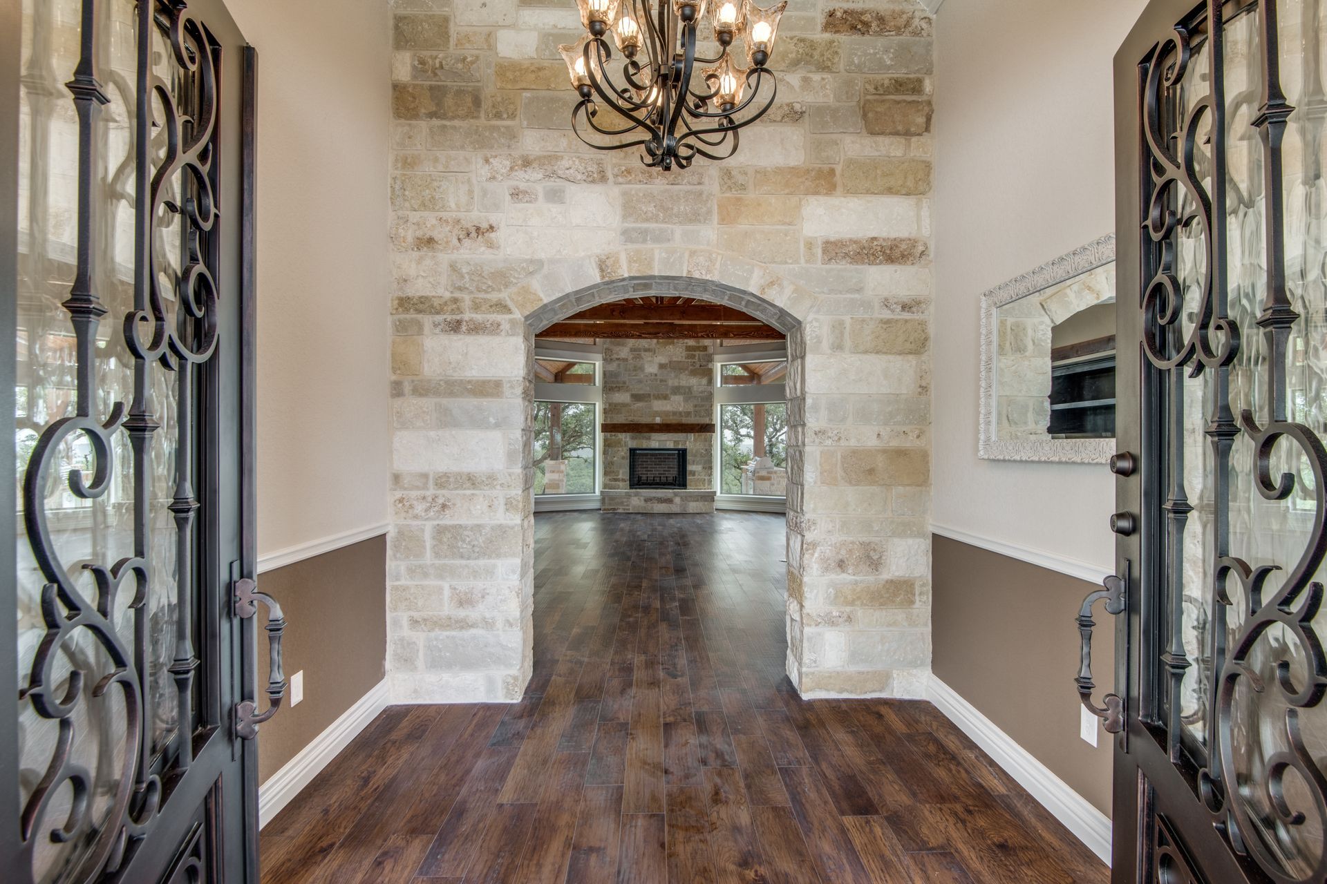 A hallway in a house with a chandelier and a brick wall.