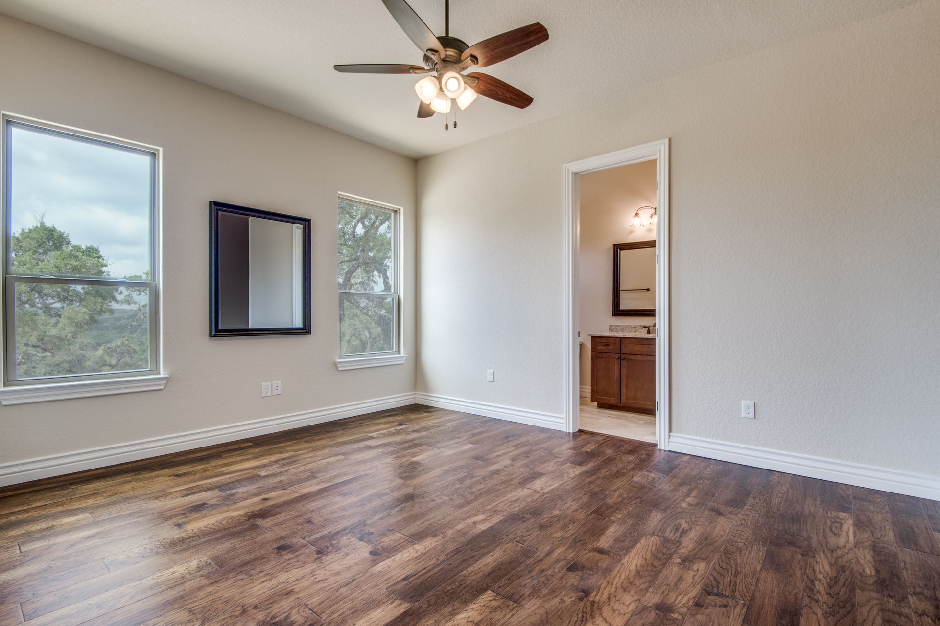 An empty bedroom with hardwood floors and a ceiling fan.