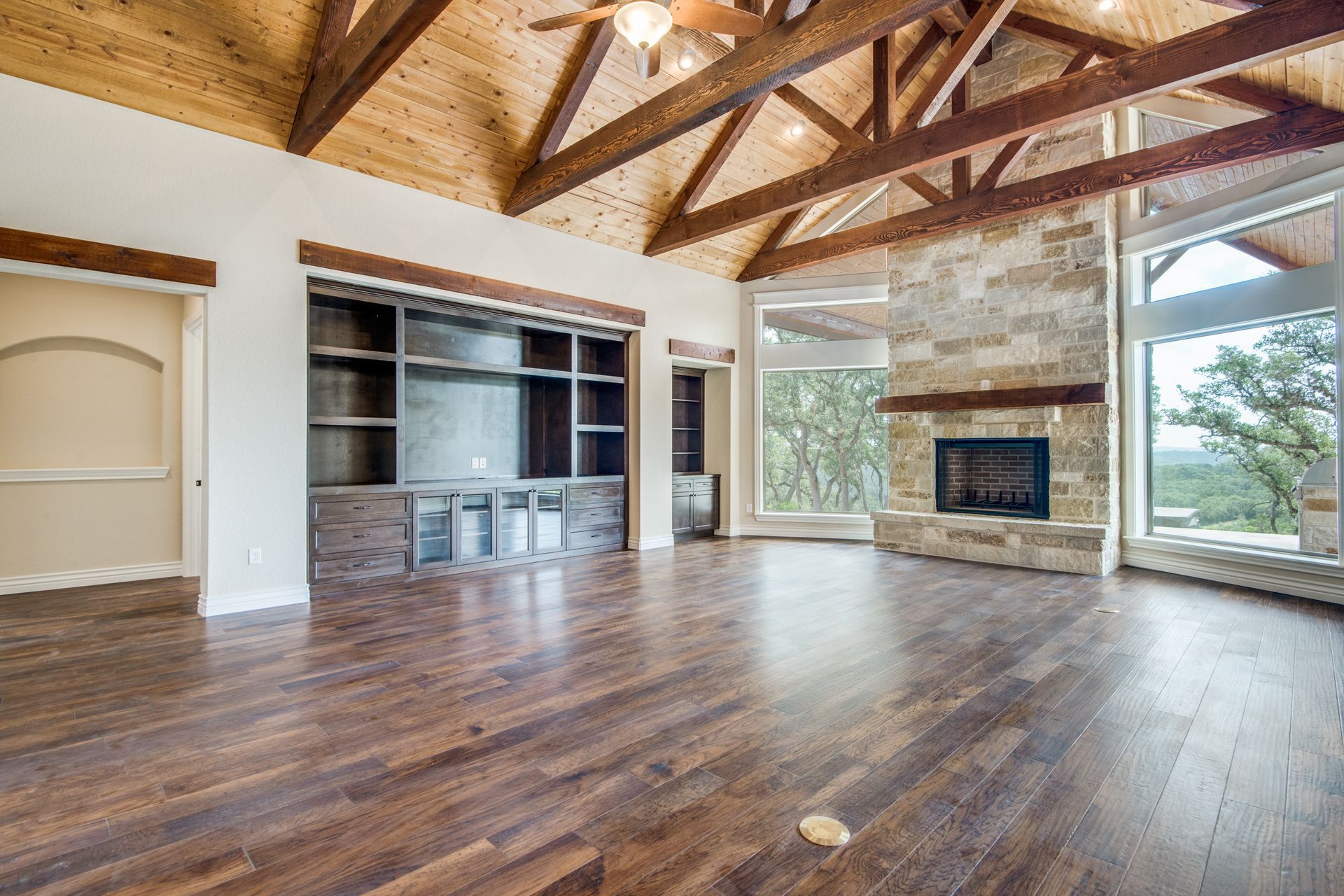 A large empty living room with hardwood floors and a fireplace.