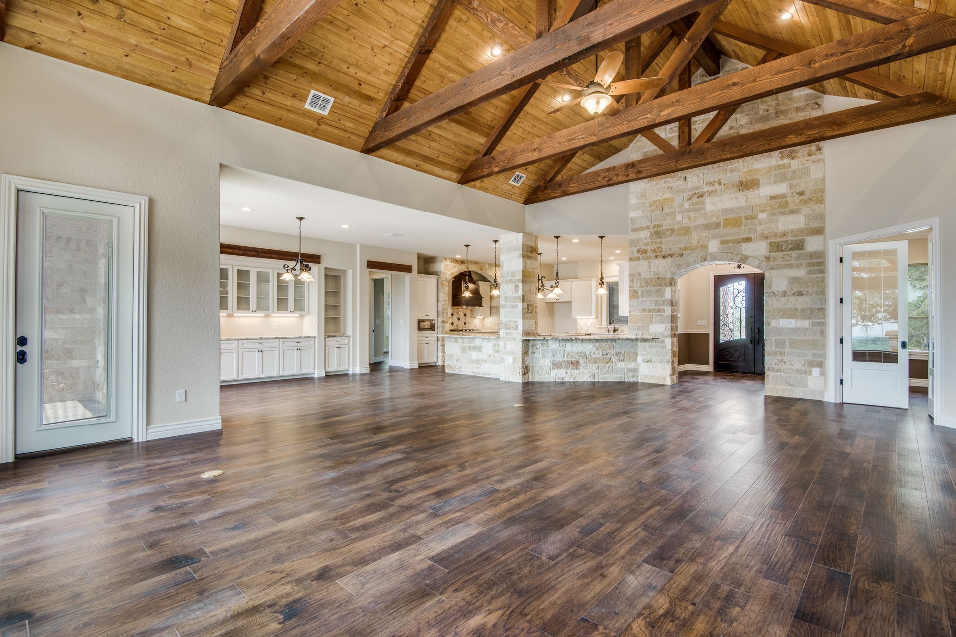 A large empty room with hardwood floors and a wooden ceiling.