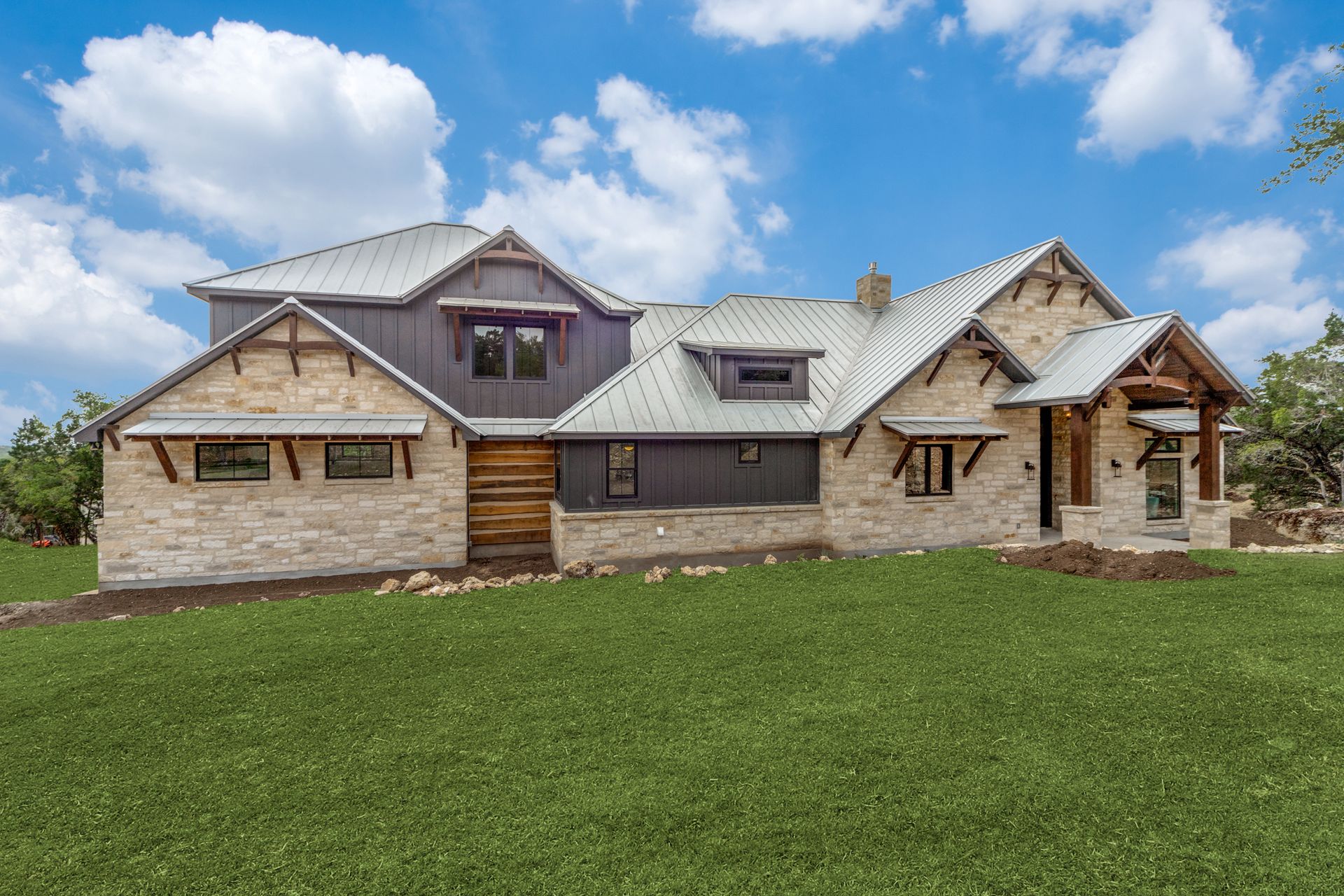 A large house with a metal roof is sitting on top of a lush green field.