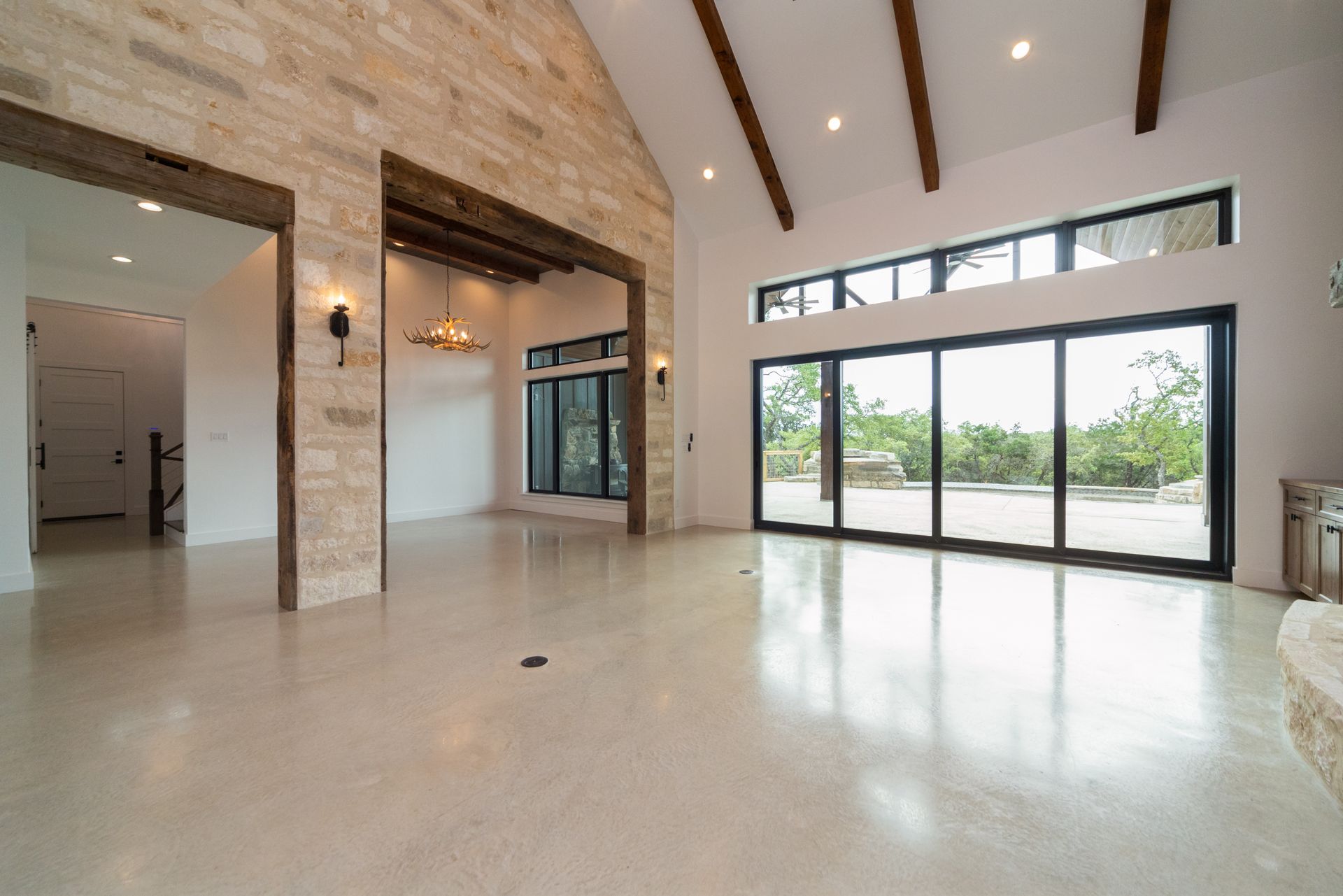 A large empty living room with a vaulted ceiling and sliding glass doors.