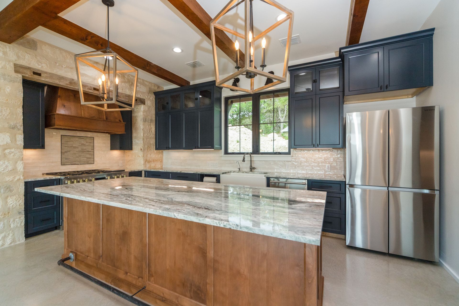 A kitchen with stainless steel appliances , wooden cabinets , granite counter tops and a large island.