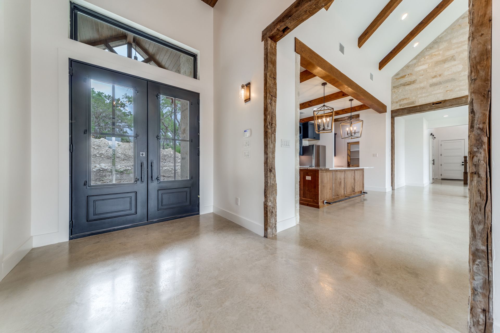 A large empty room in a house with a vaulted ceiling and wooden beams.