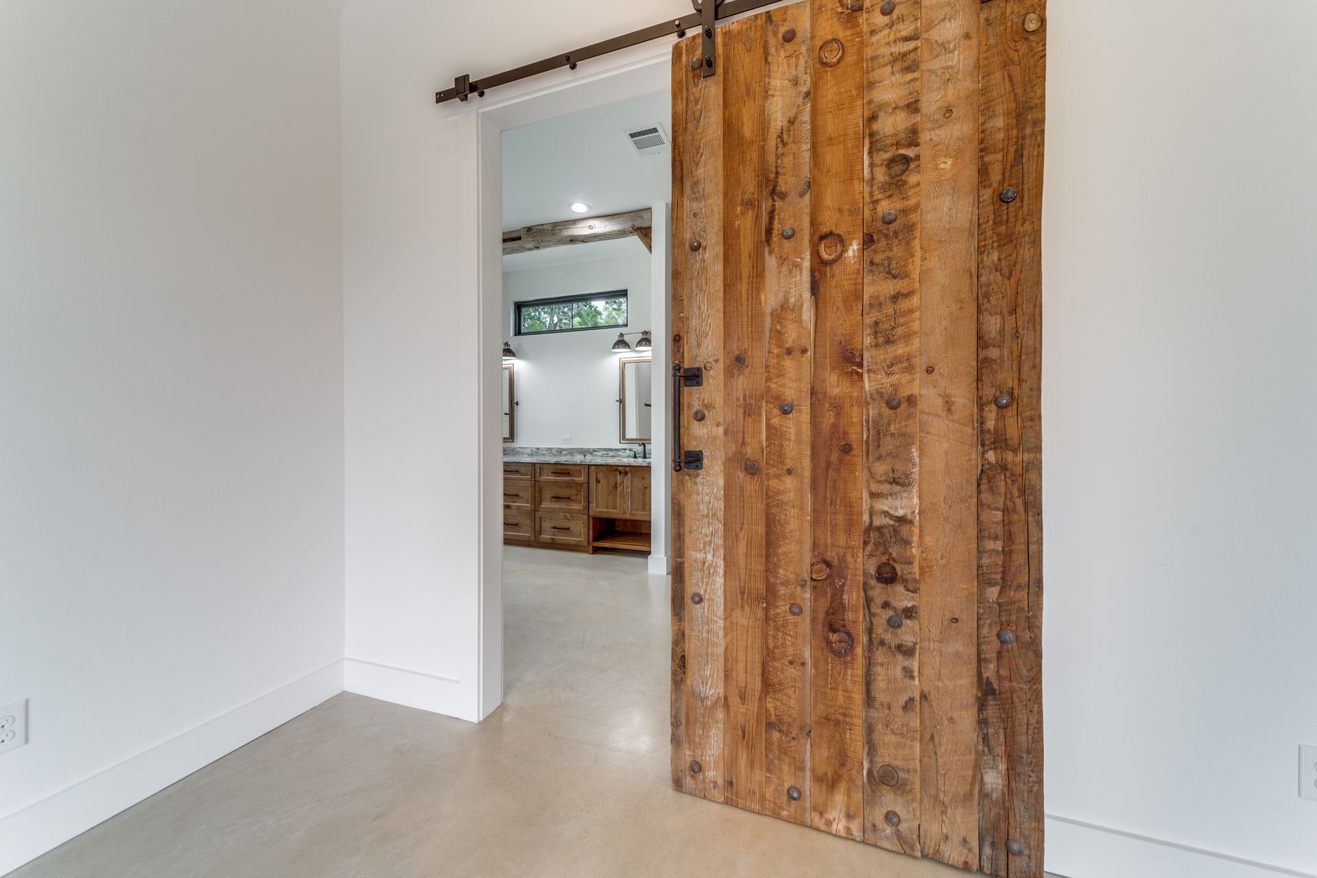 A bedroom with a wooden sliding barn door leading to a bathroom.