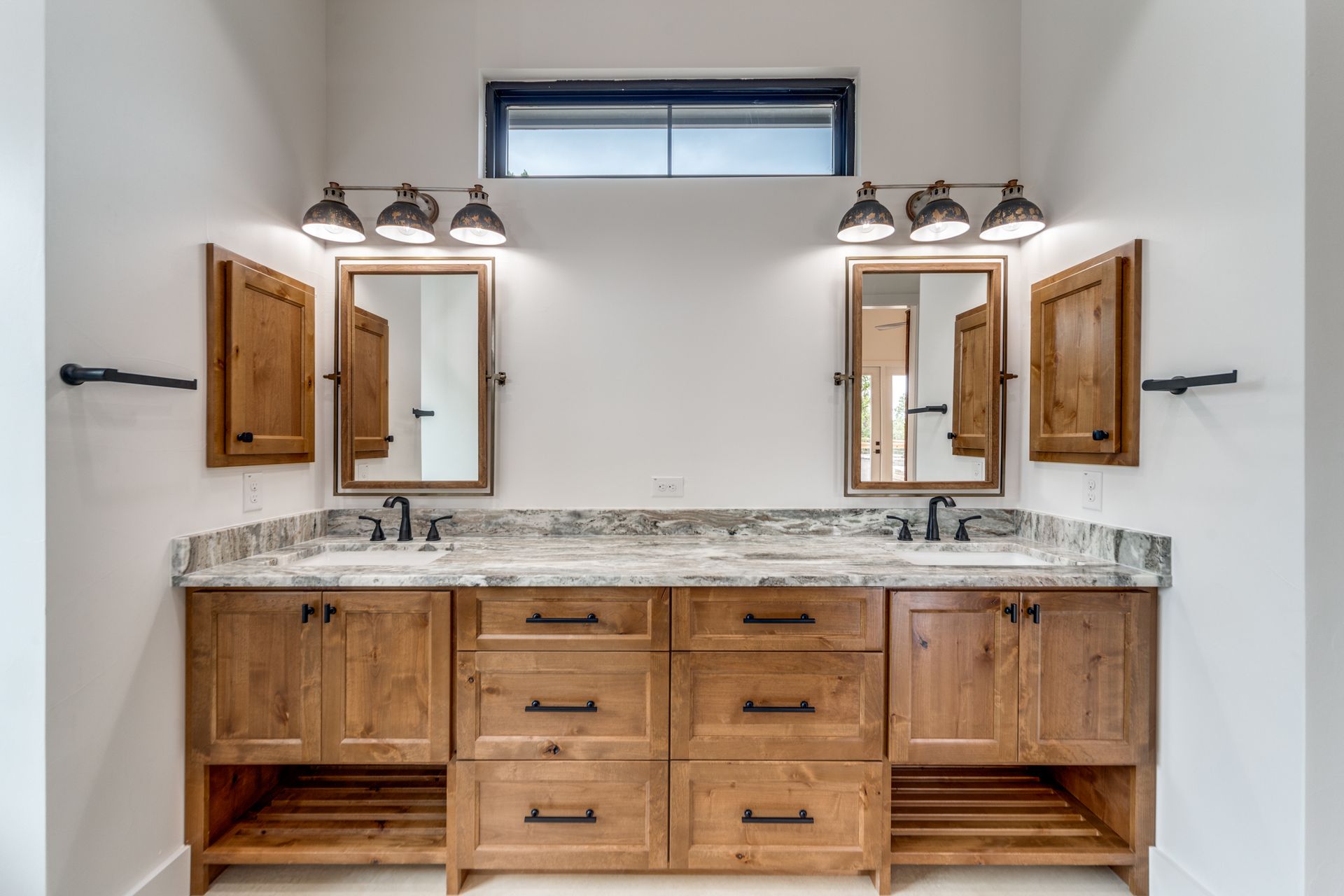 A bathroom with two sinks , two mirrors , and wooden cabinets.