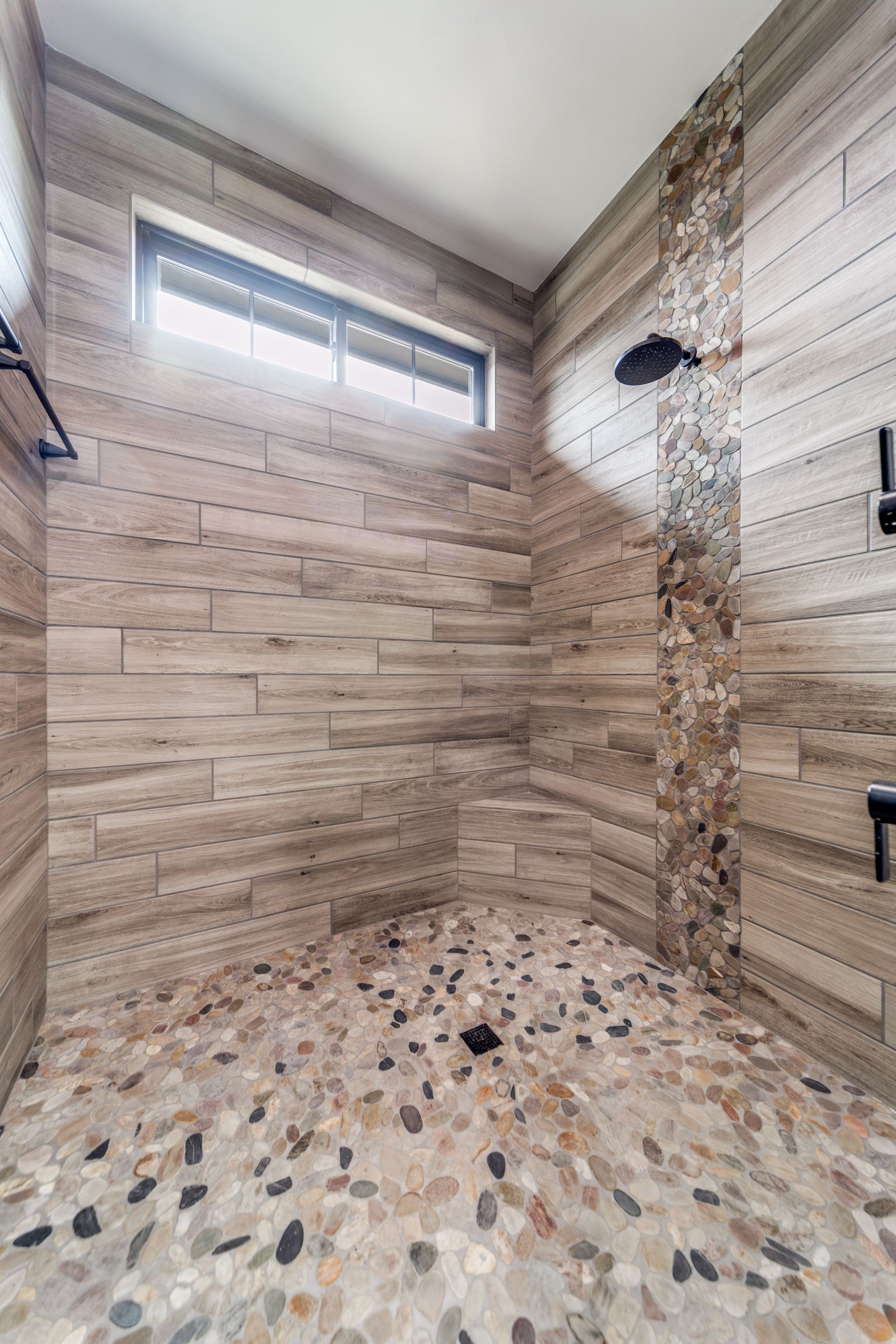 A bathroom with a walk in shower and a window.