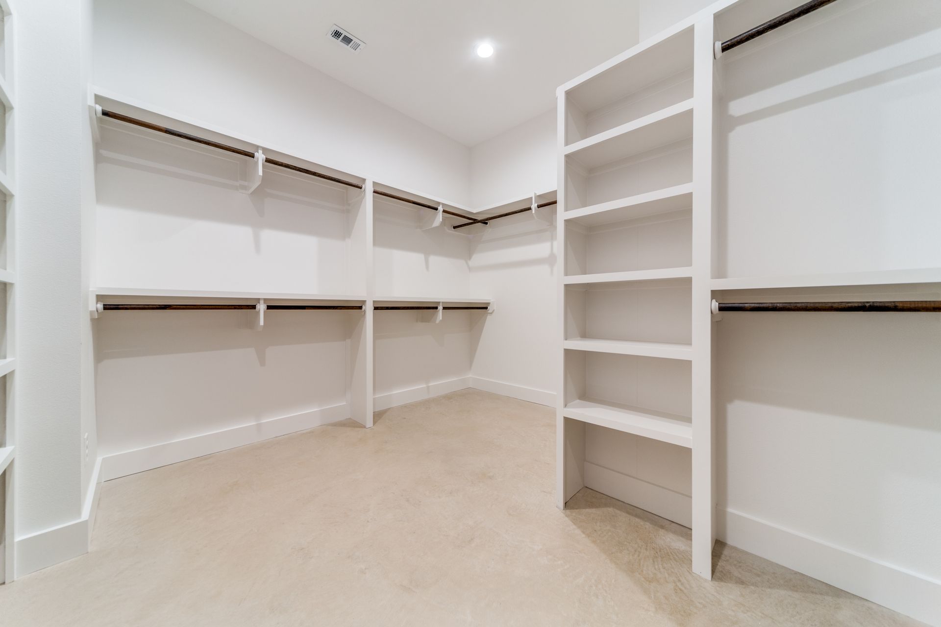 An empty walk in closet with lots of shelves and clothes racks.