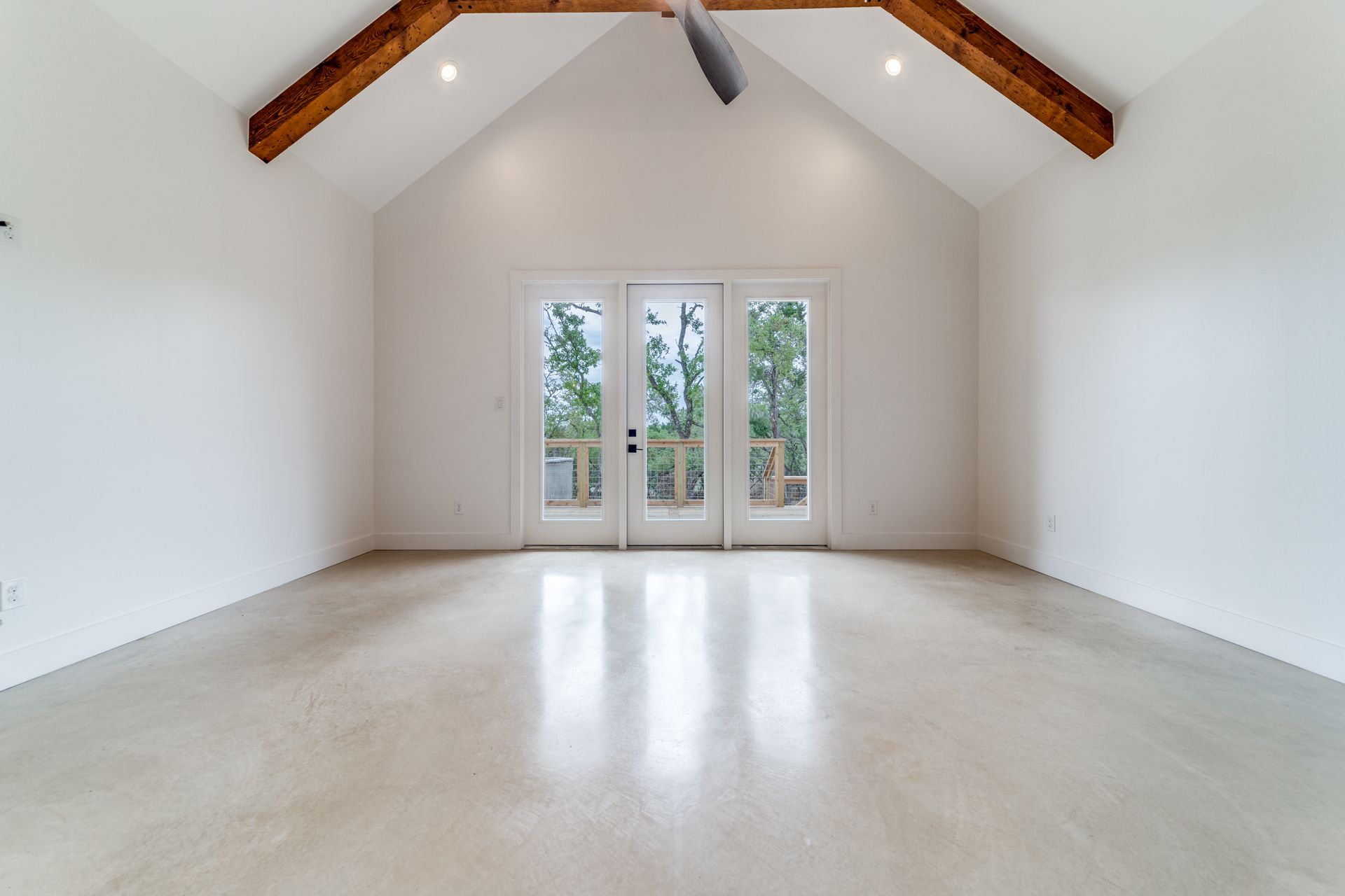 An empty room with a vaulted ceiling and a ceiling fan.