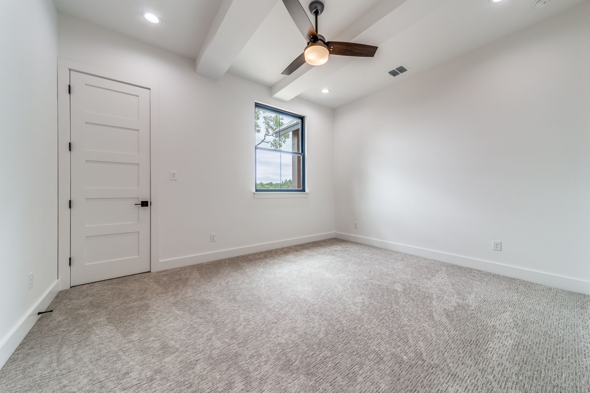 An empty bedroom with a ceiling fan and a window.