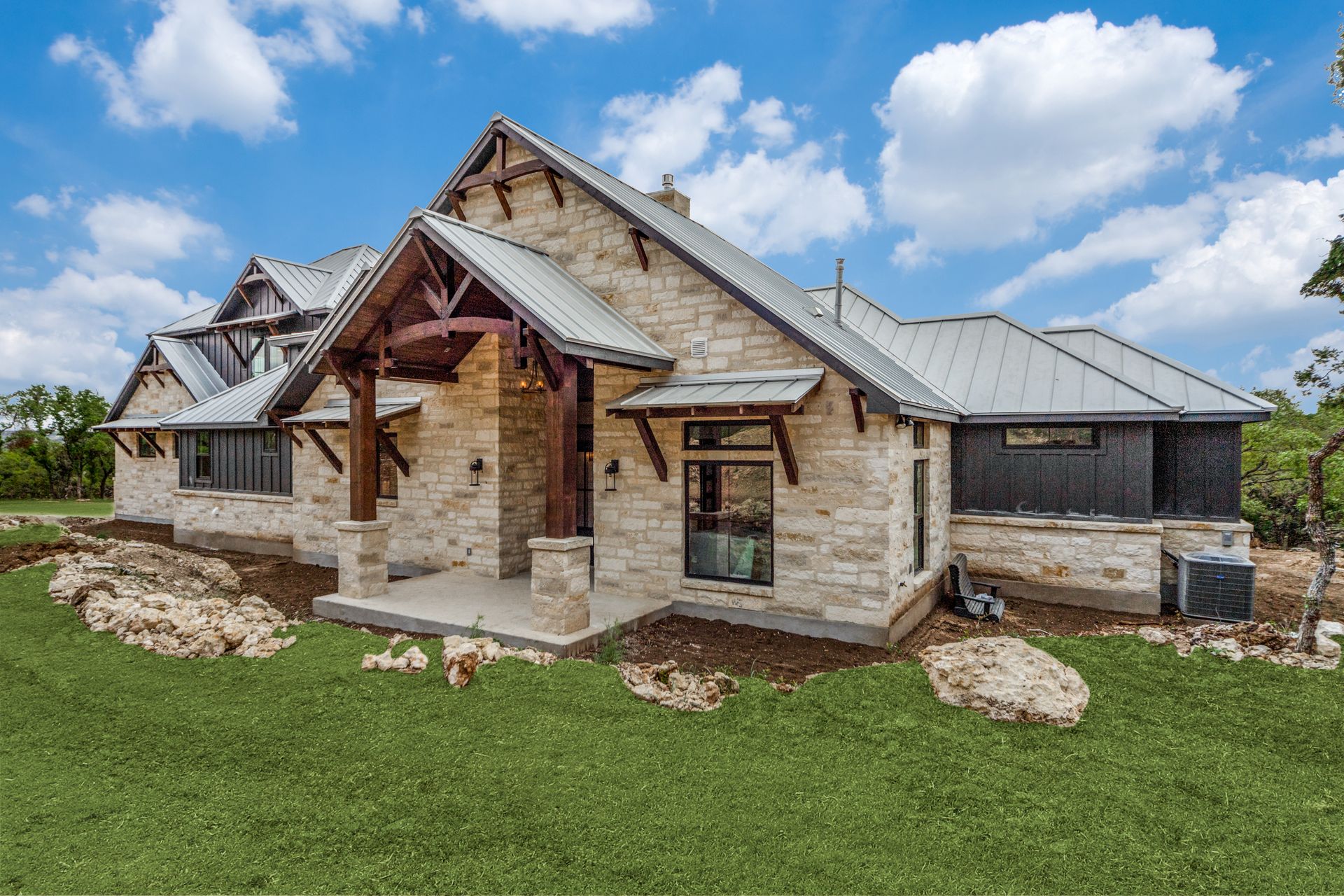 A large brick house with a metal roof is sitting on top of a lush green field.