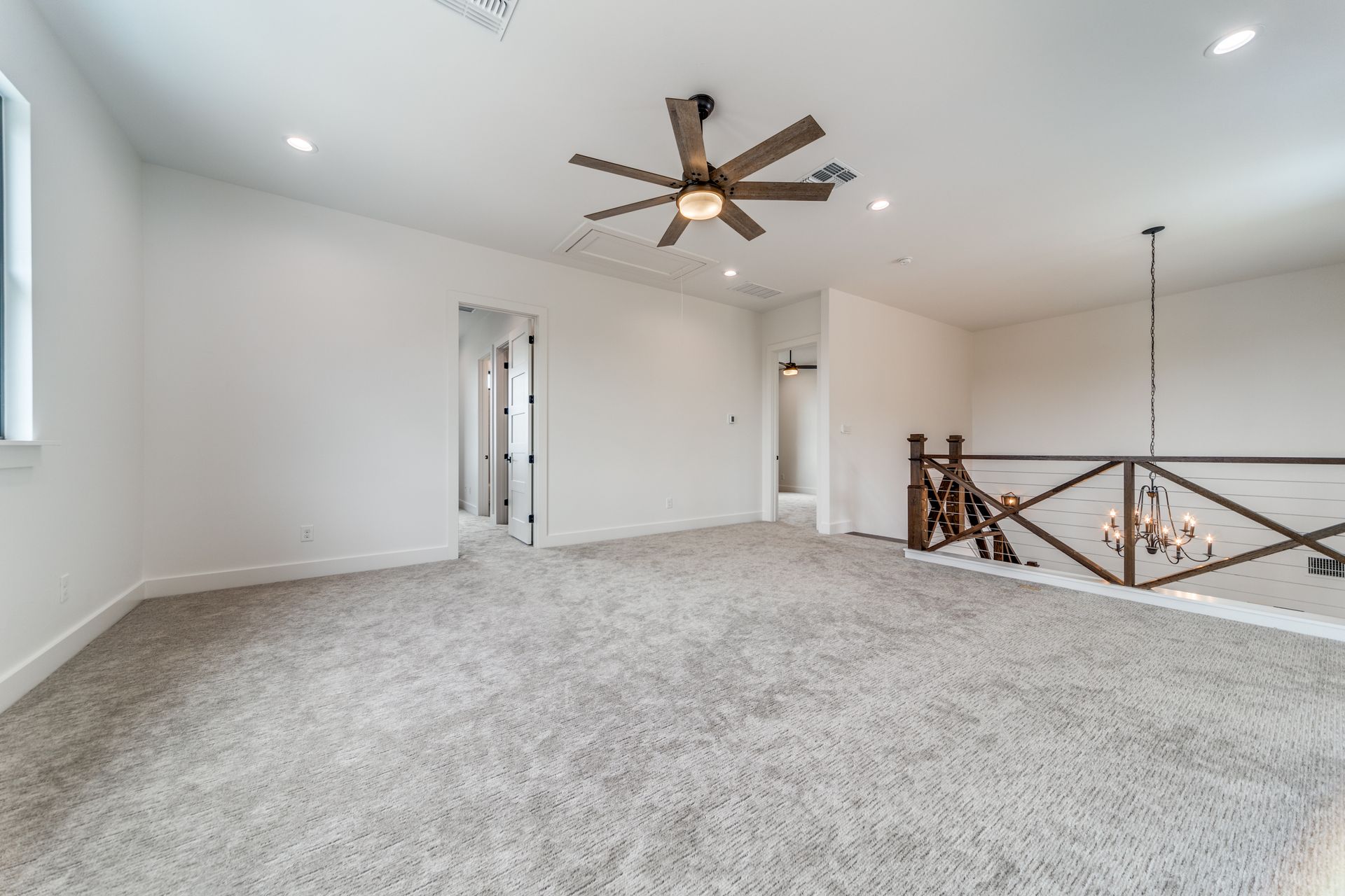 An empty room with a ceiling fan and a railing.