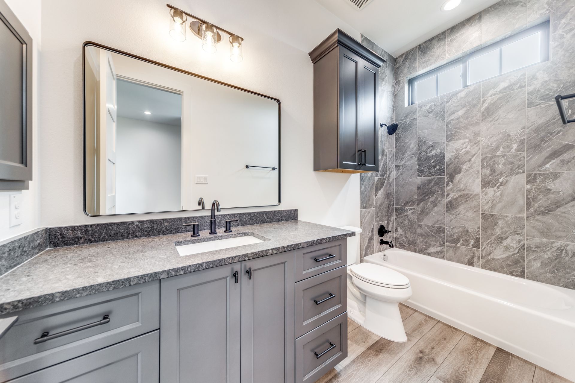A bathroom with a sink , toilet , bathtub and mirror.