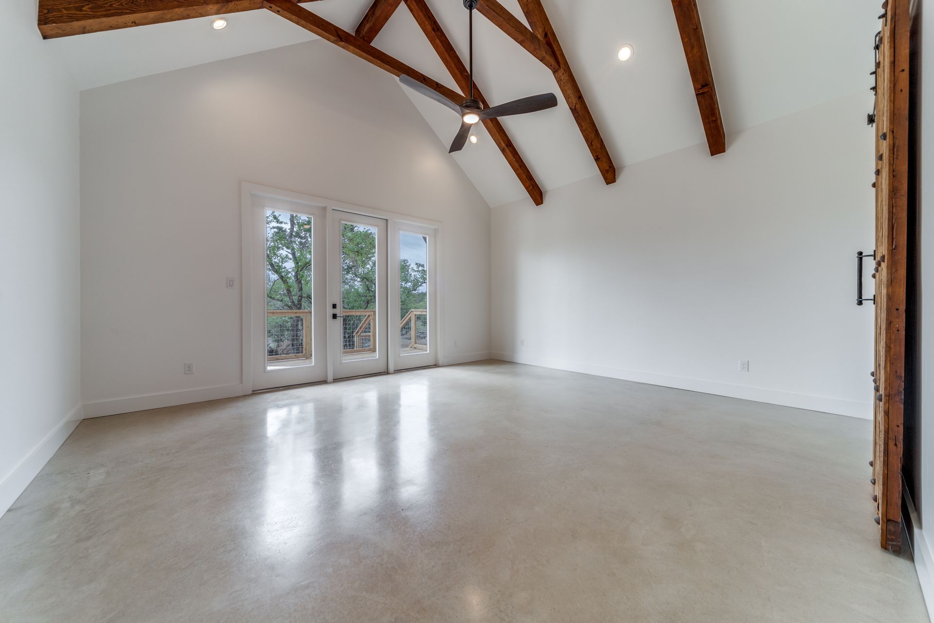 A large empty room with a ceiling fan and a lot of windows.