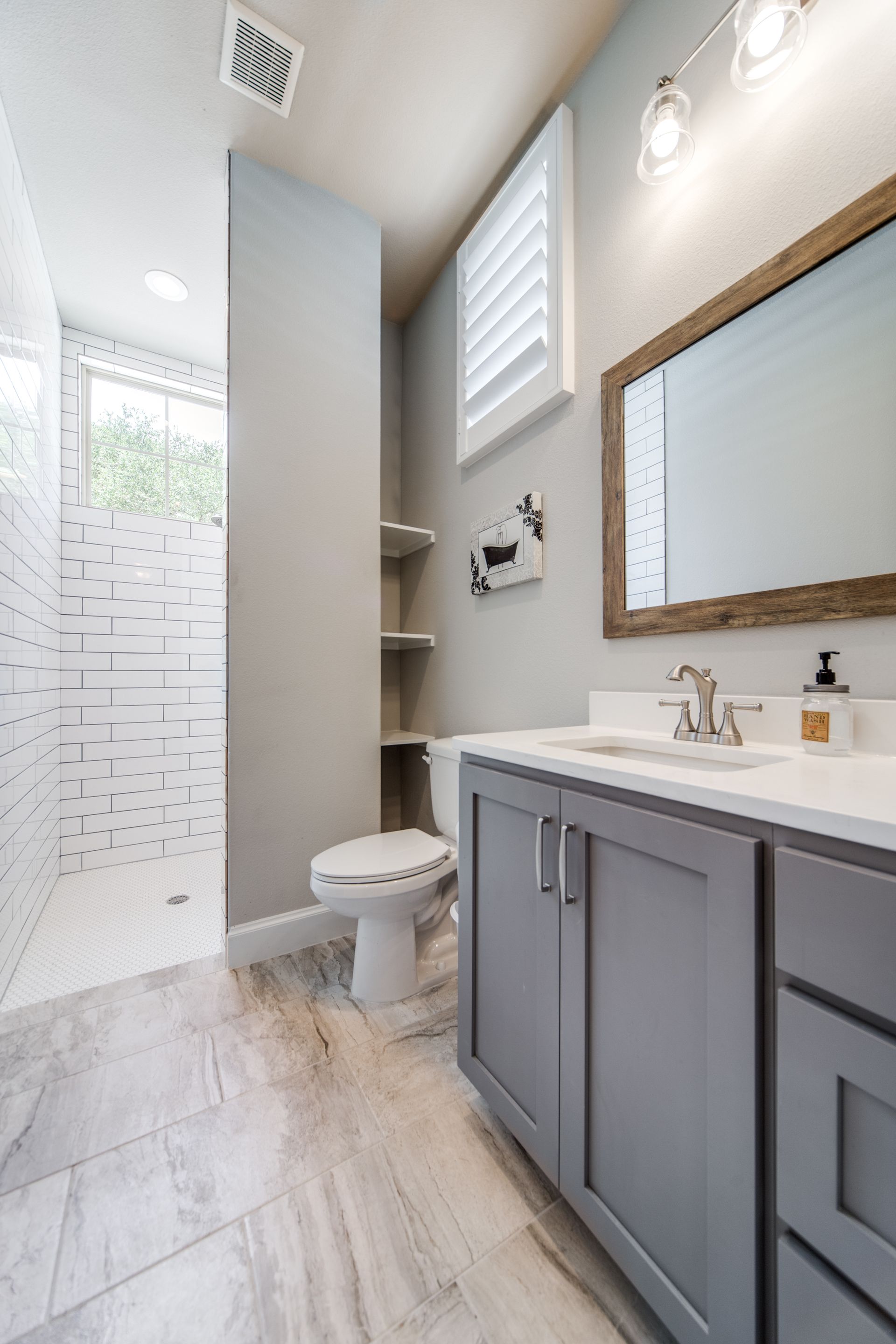 A bathroom with a toilet , sink , mirror and walk in shower.