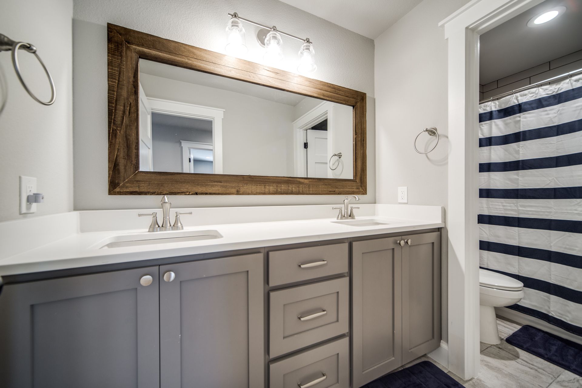A bathroom with two sinks , a large mirror and a striped shower curtain.