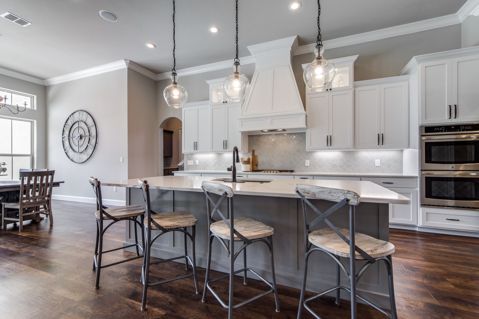 A kitchen with white cabinets and stools and a large island.