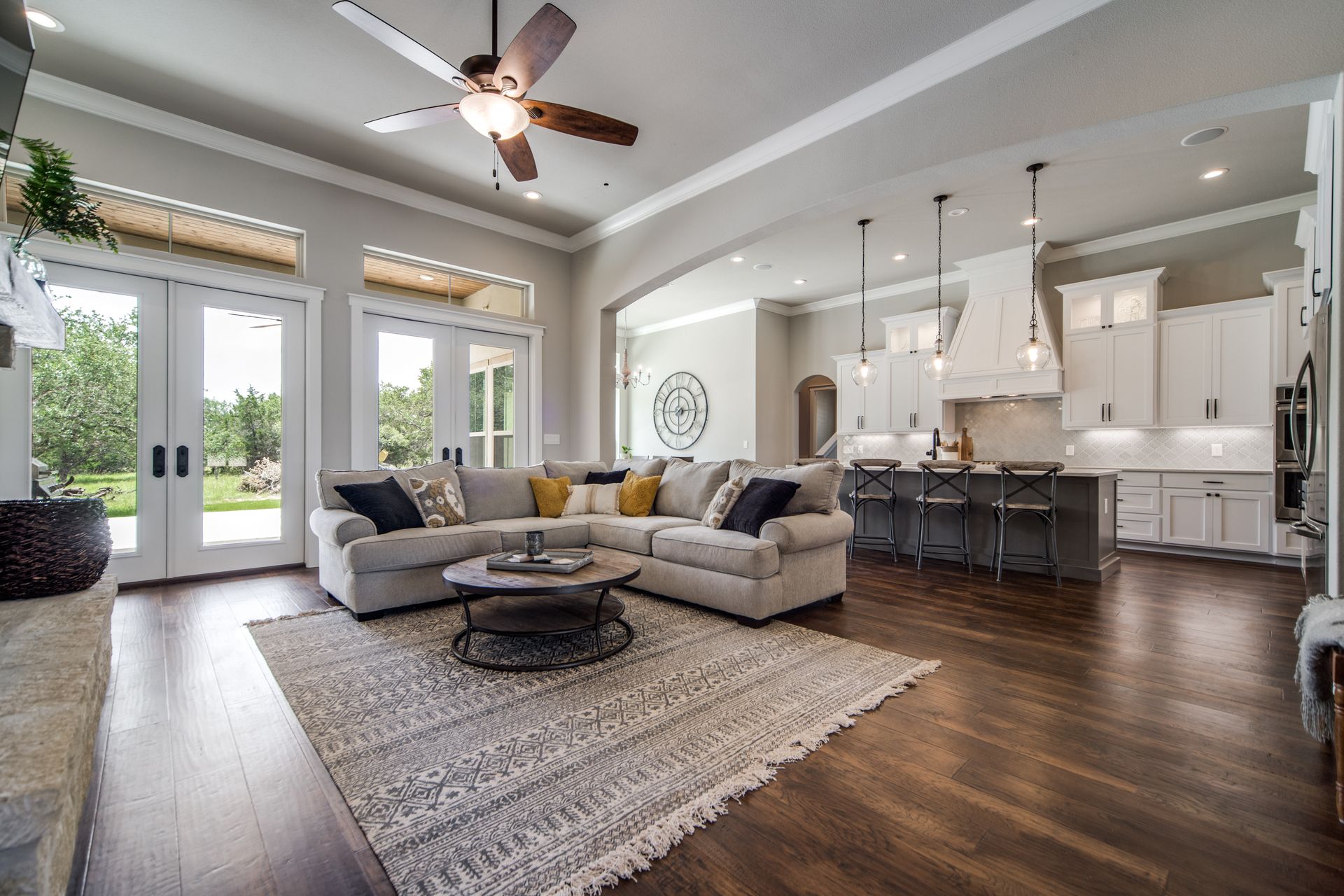 A living room with a sectional couch , coffee table , and ceiling fan.