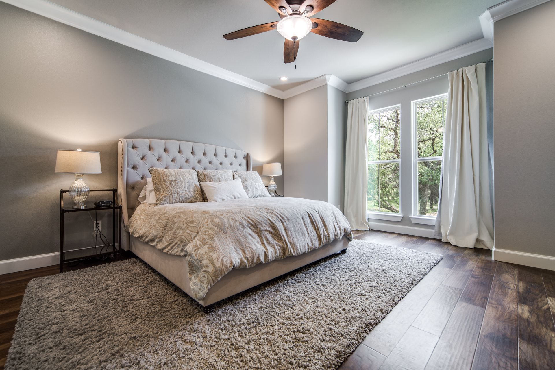 There is a ceiling fan in the bedroom with a large bed.