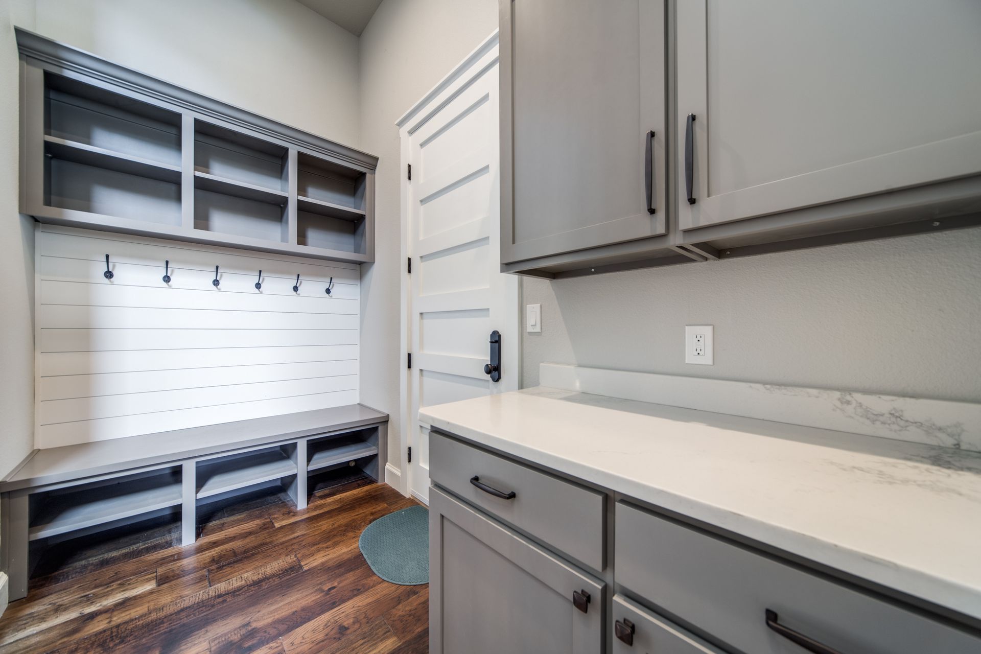 A laundry room with gray cabinets and wooden floors.
