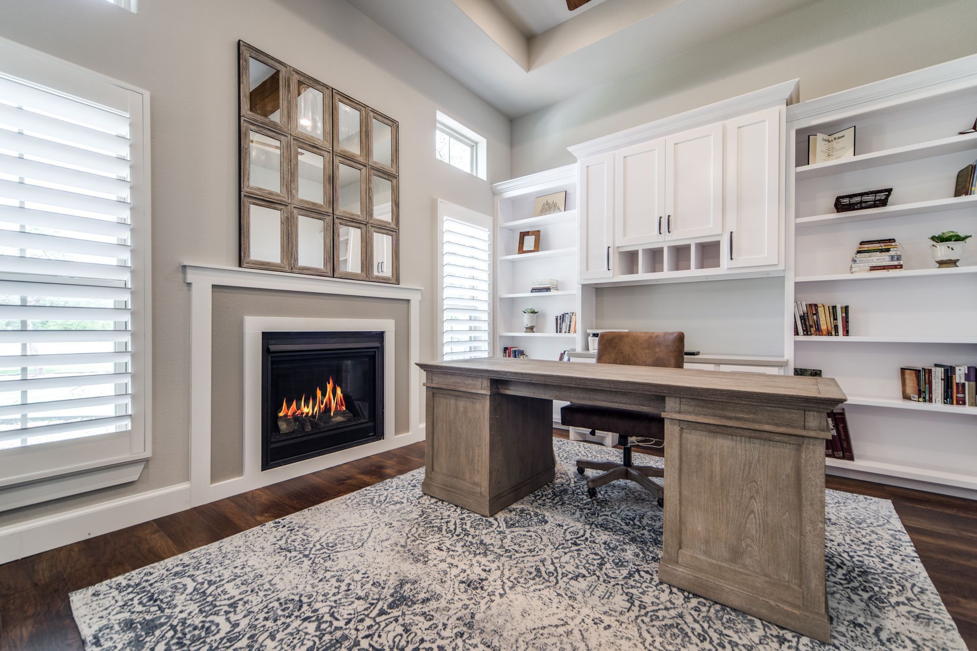 A home office with a desk , chair and fireplace.