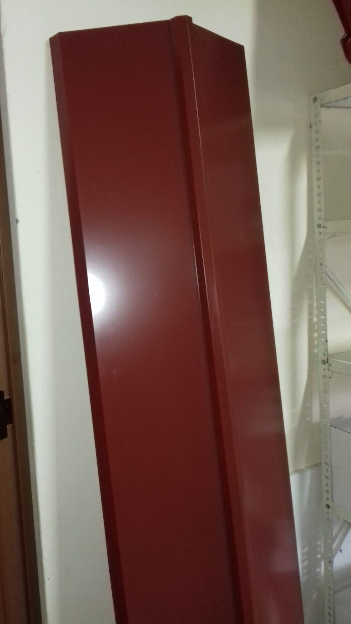 Destello metálico rojo apoyado sobre una pared blanca.