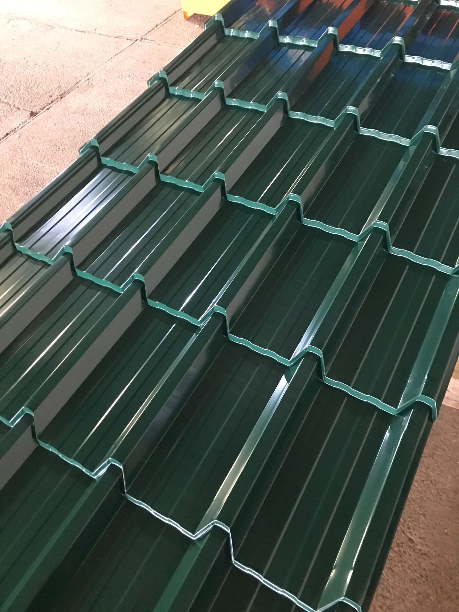 Tejas metálicas verdes apiladas, creando una superficie estampada.