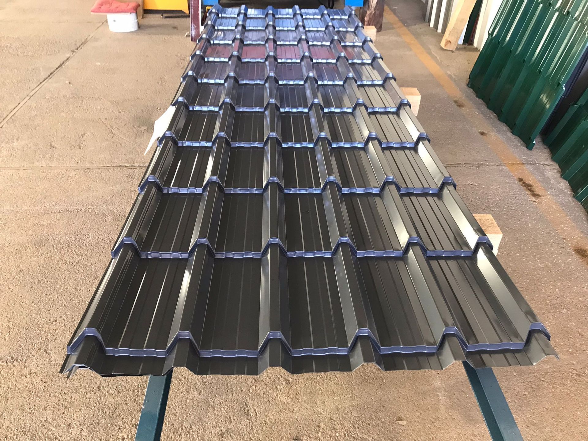 Panel de techo de metal oscuro sobre una superficie de trabajo, vista en ángulo.