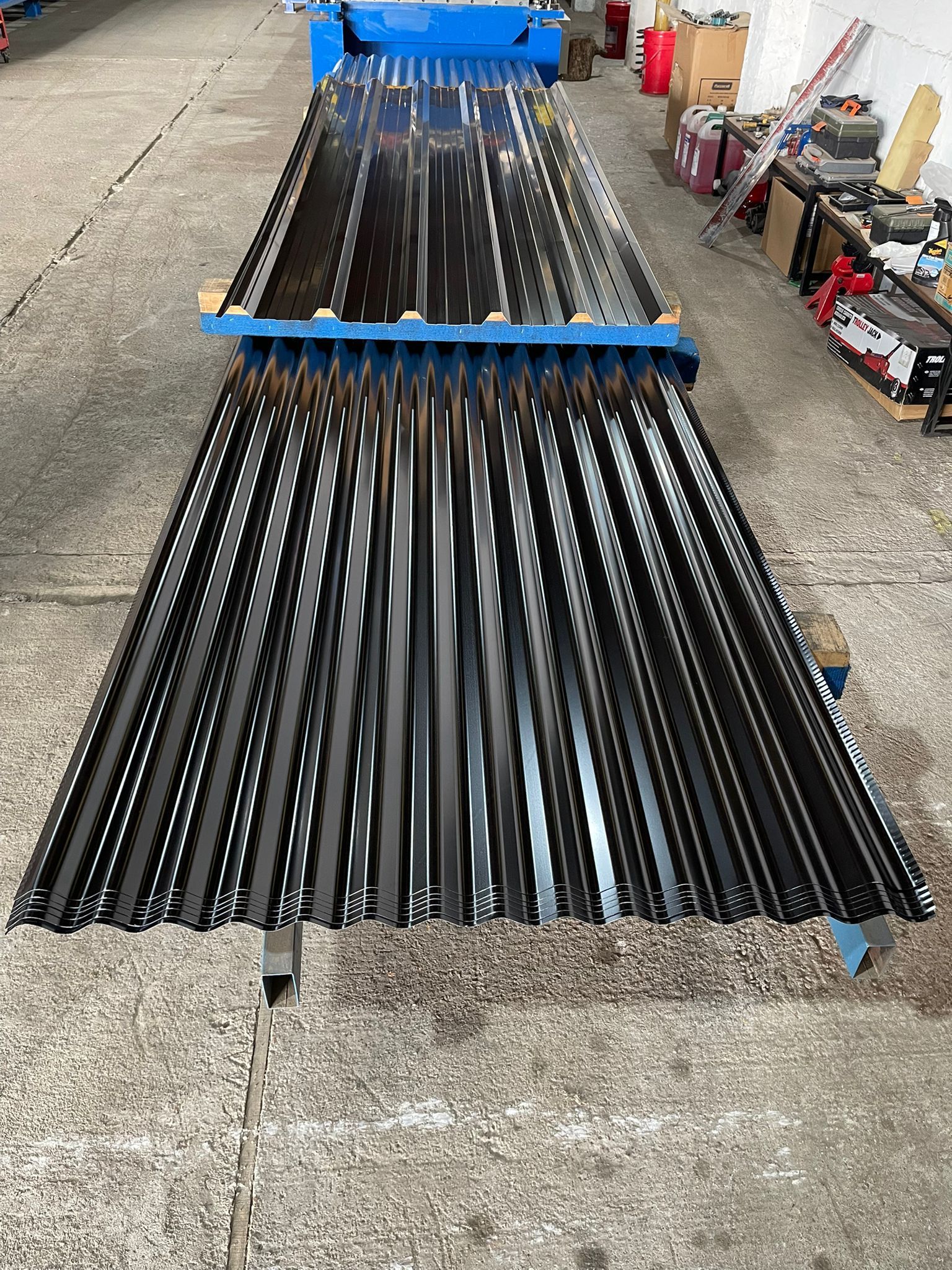 Láminas de techo de metal corrugado negro sobre una mesa de producción de fábrica.