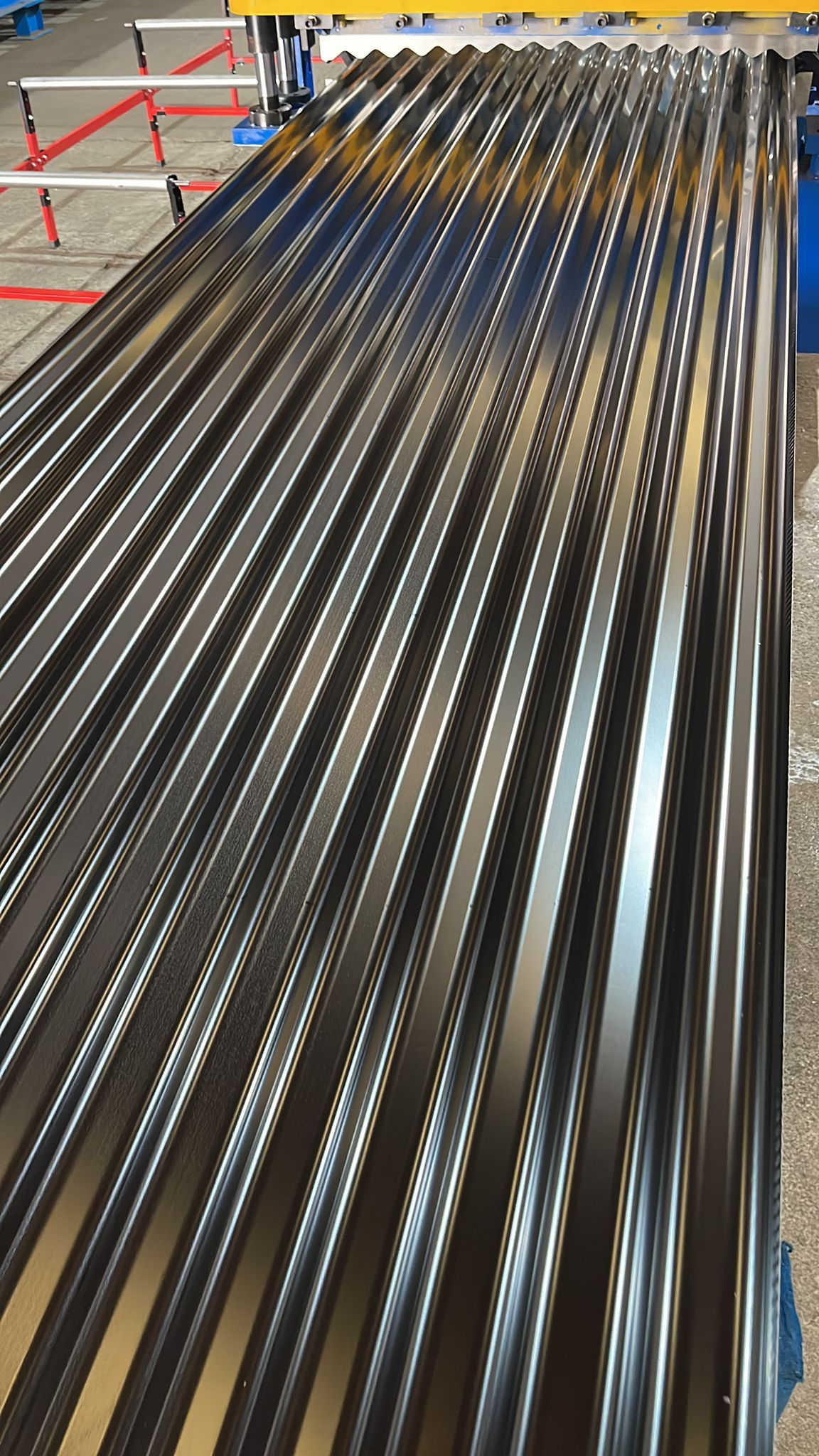 Chapa ondulada, color metalizado oscuro, ambientación industrial, crestas y valles repetidos.