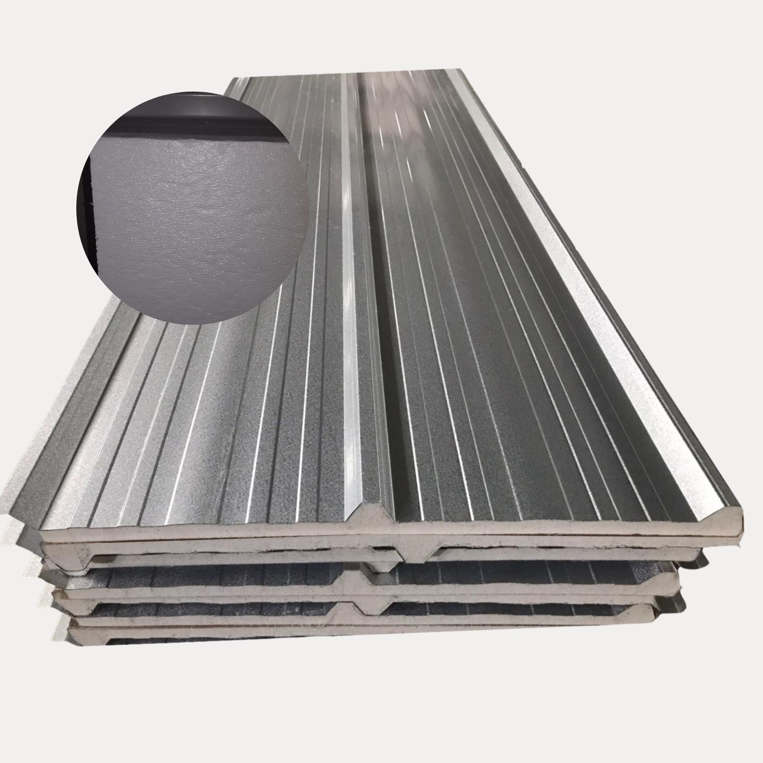 Pila de paneles sándwich de metal corrugado, de color gris, con un primer plano de la superficie texturizada.