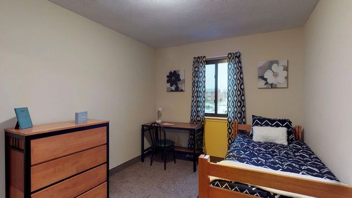 Bedroom with bed, table and dresser photo