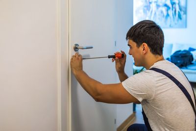 A Man Is Fixing a Door Handle with A Screwdriver | Westminster, CO | M.L. Locksmith