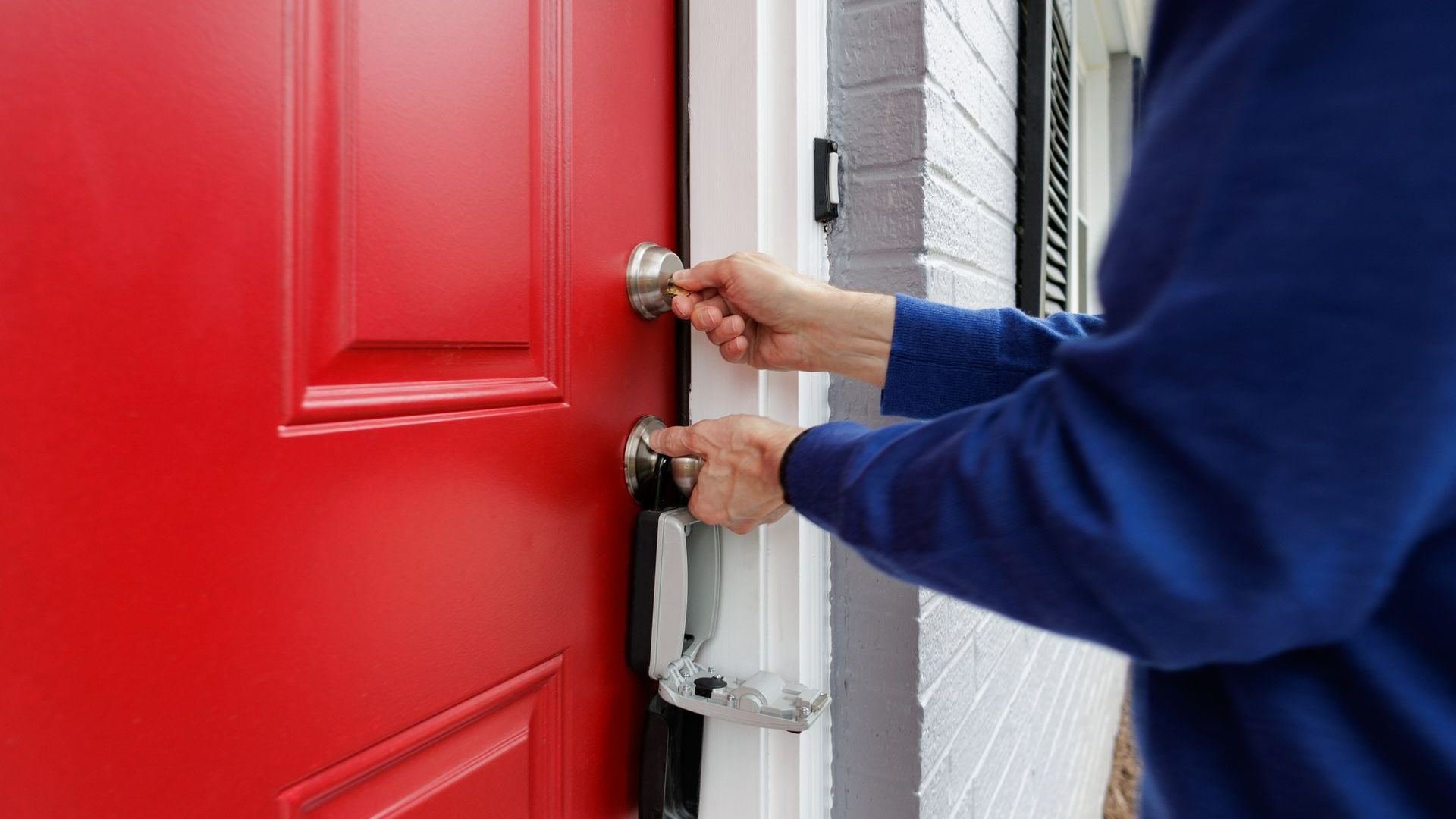 A Person Is Opening a Red Door with A Key | Westminster, CO | M.L. Locksmith