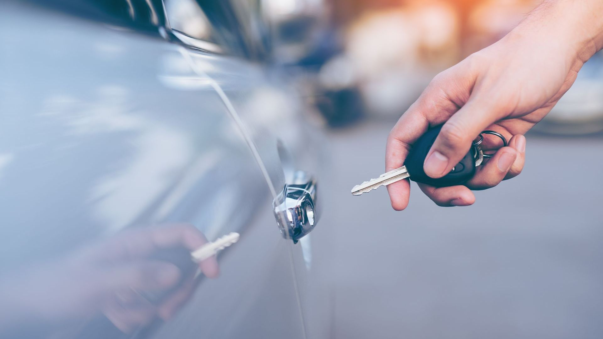 A Person Is Holding a Car Key in Front of A Car | Westminster, CO | M.L. Locksmith