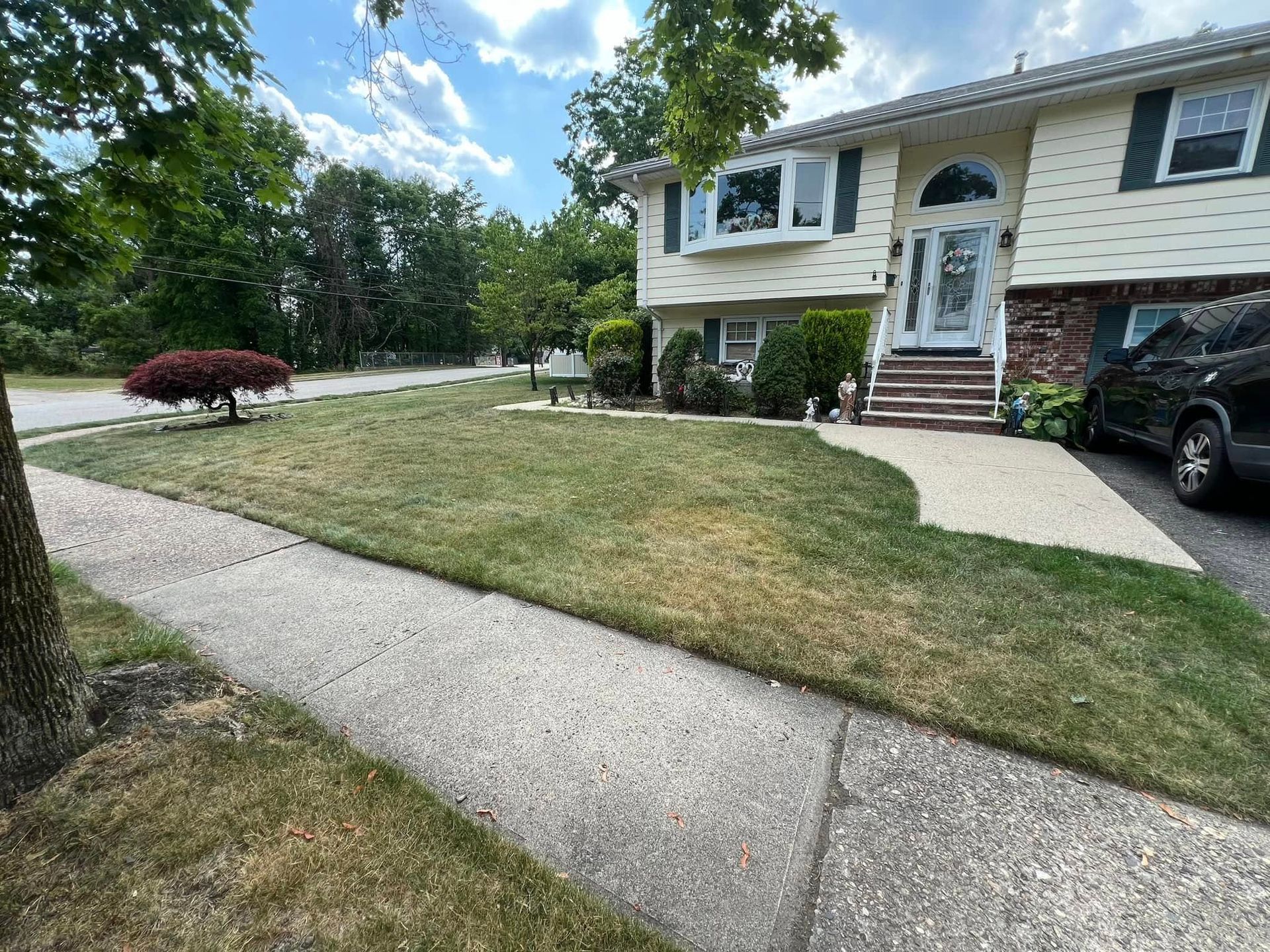 A house with a lush green lawn and a car parked in front of it.