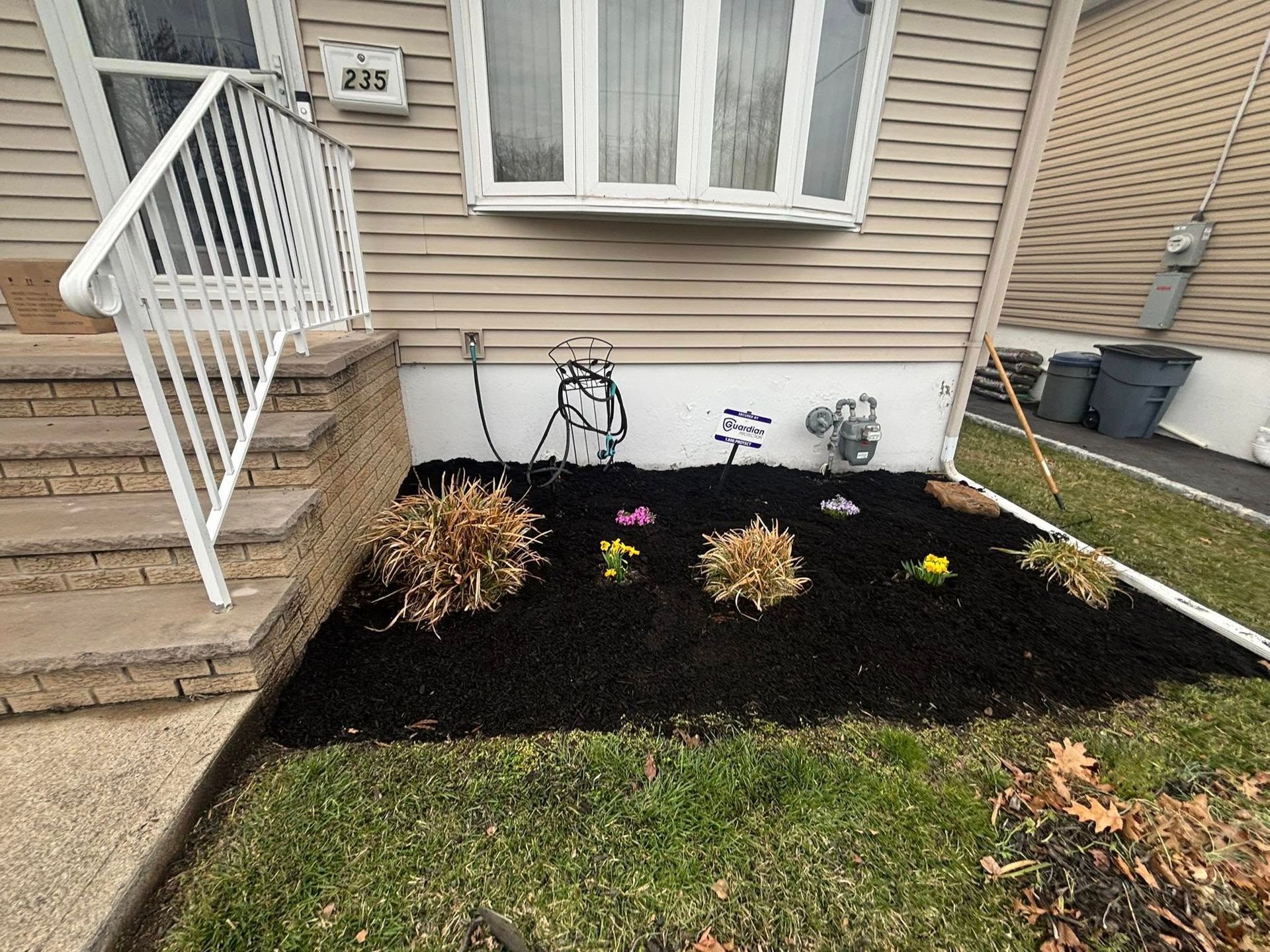 A lawn with flowers and mulch in front of a house.