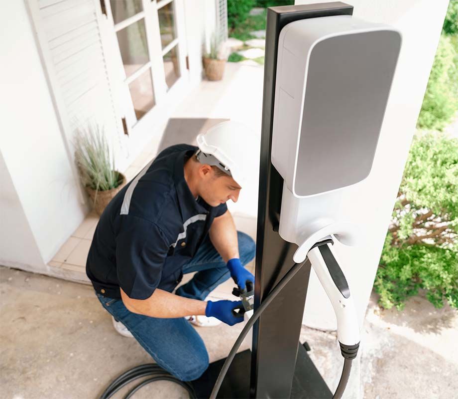 A man is working on an electric vehicle charging station.