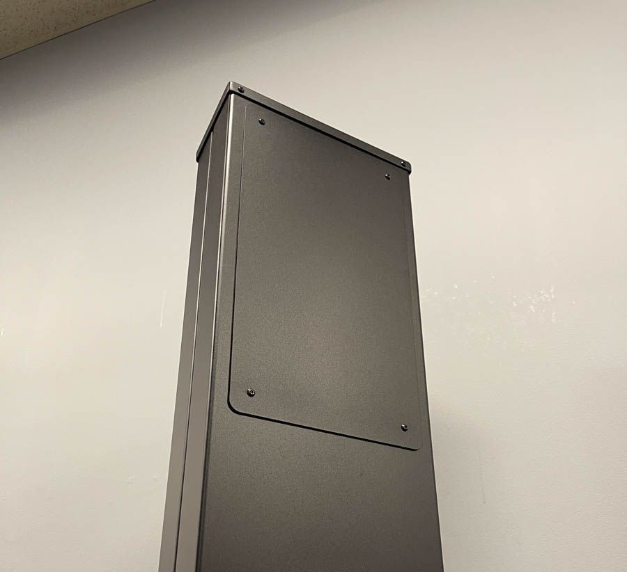 A black box is sitting on a white wall.