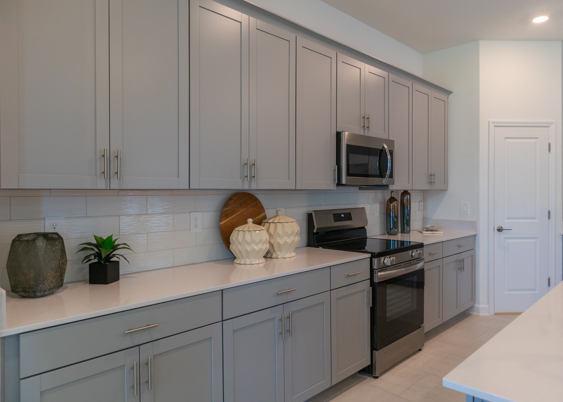 Gray kitchen with cabinets, white countertops, stainless steel appliances.