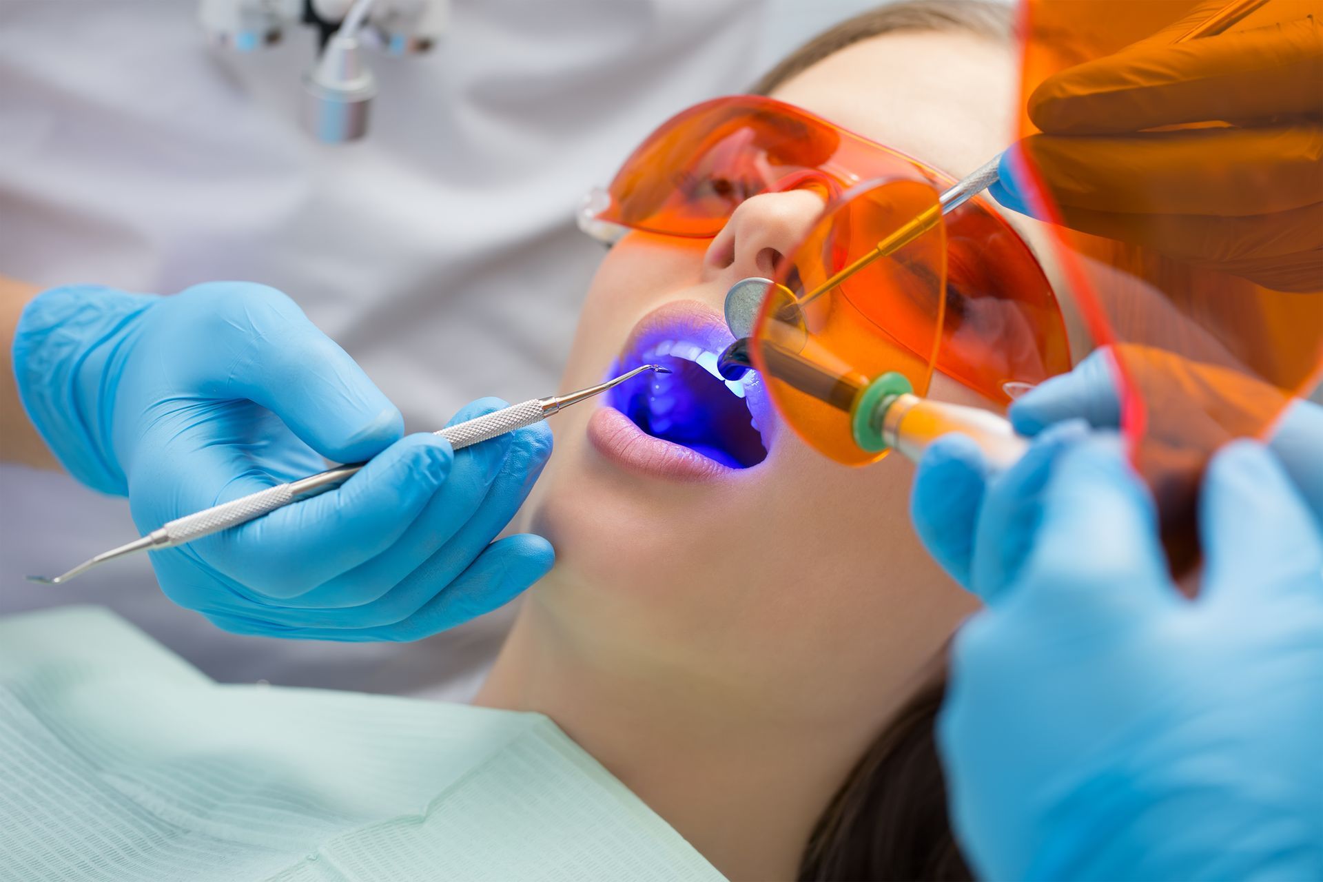 A general dentist is performing a tooth filling using an ultraviolet lamp on a patient.