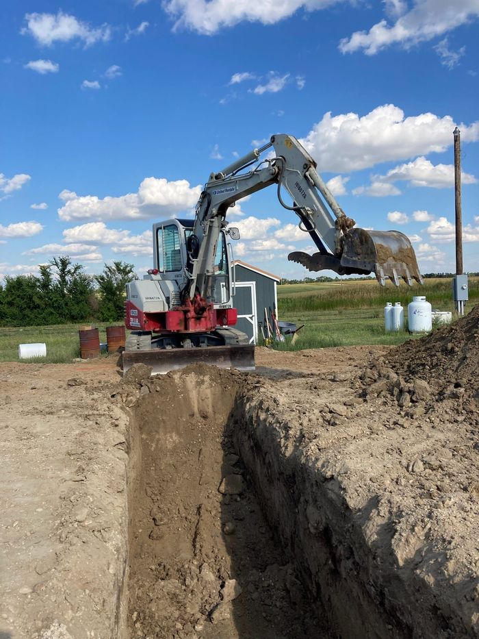 An excavator is digging a hole in the dirt in a field.