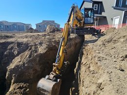 A yellow excavator is digging a hole in the ground.