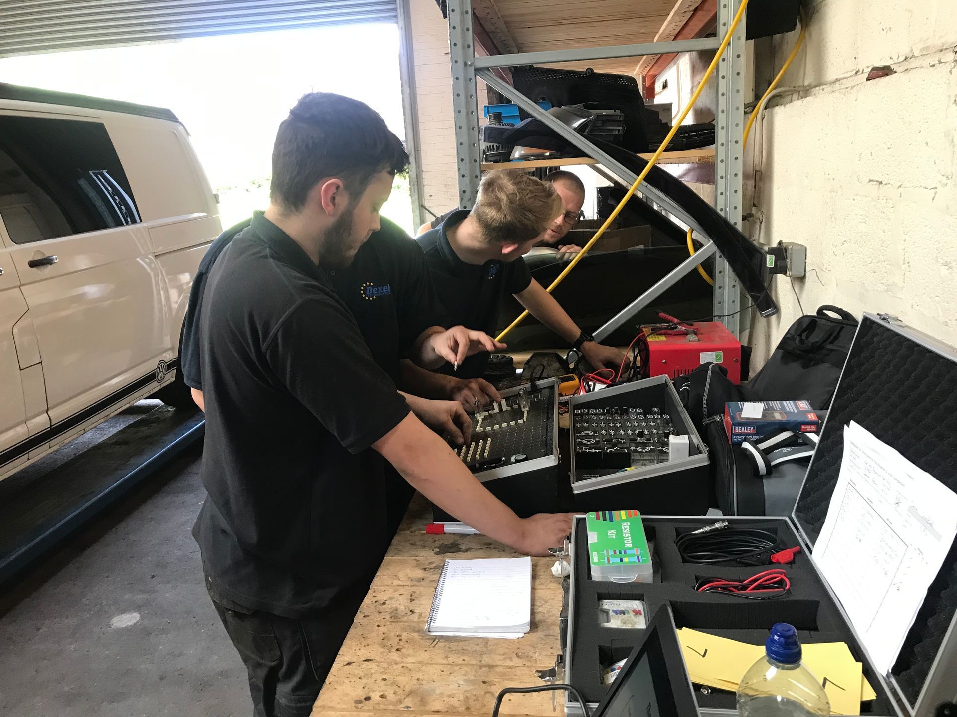 Two men are working on a computer in a garage.