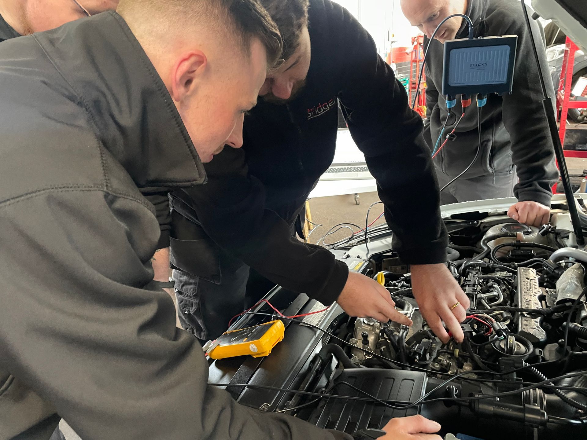 A group of men are working on a car engine.