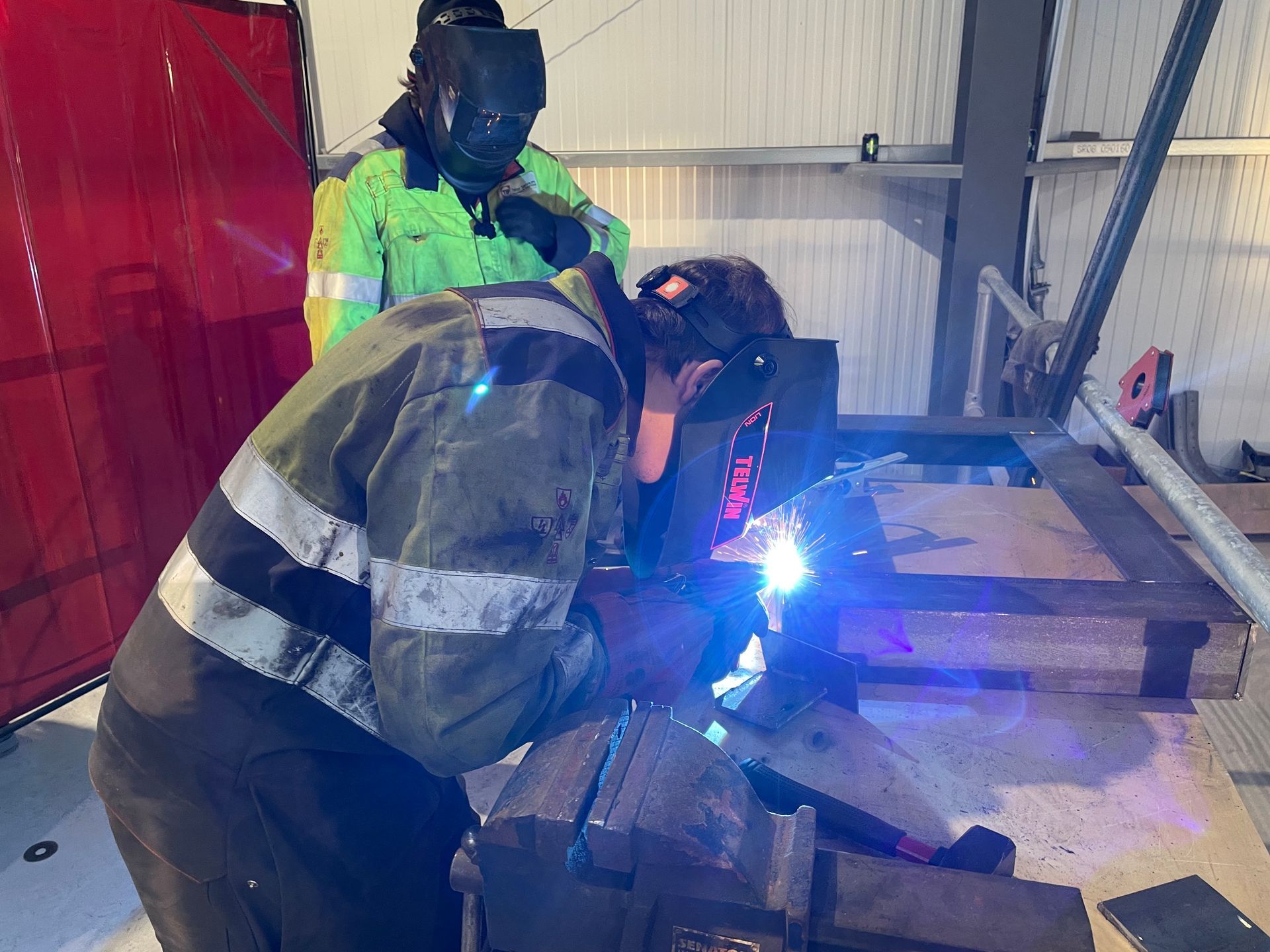 A man is welding a piece of metal in a factory.