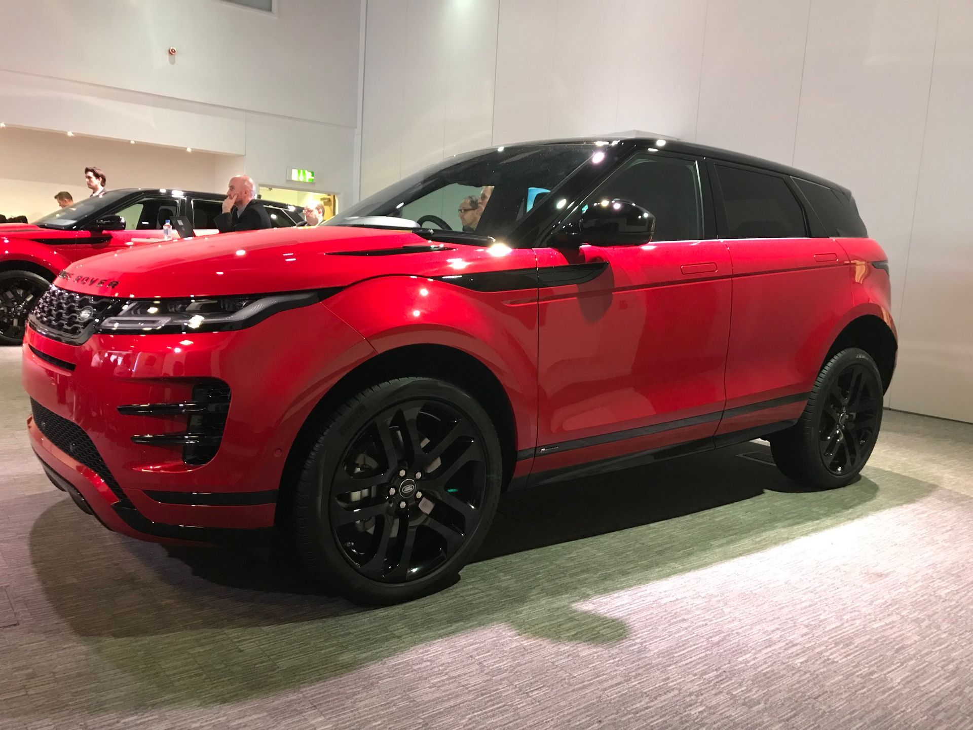 A red range rover evoque is parked in a showroom.